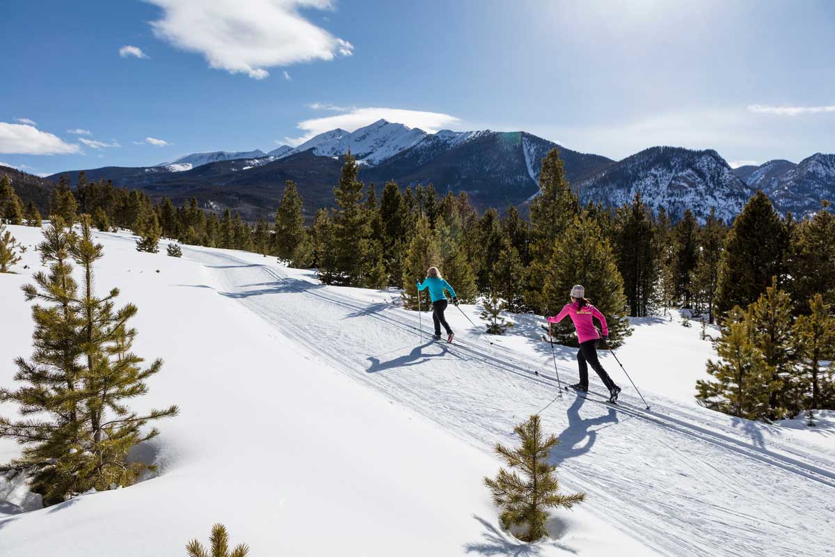 Scenic view of the trails and mountains with two women nordic skiing in the distance