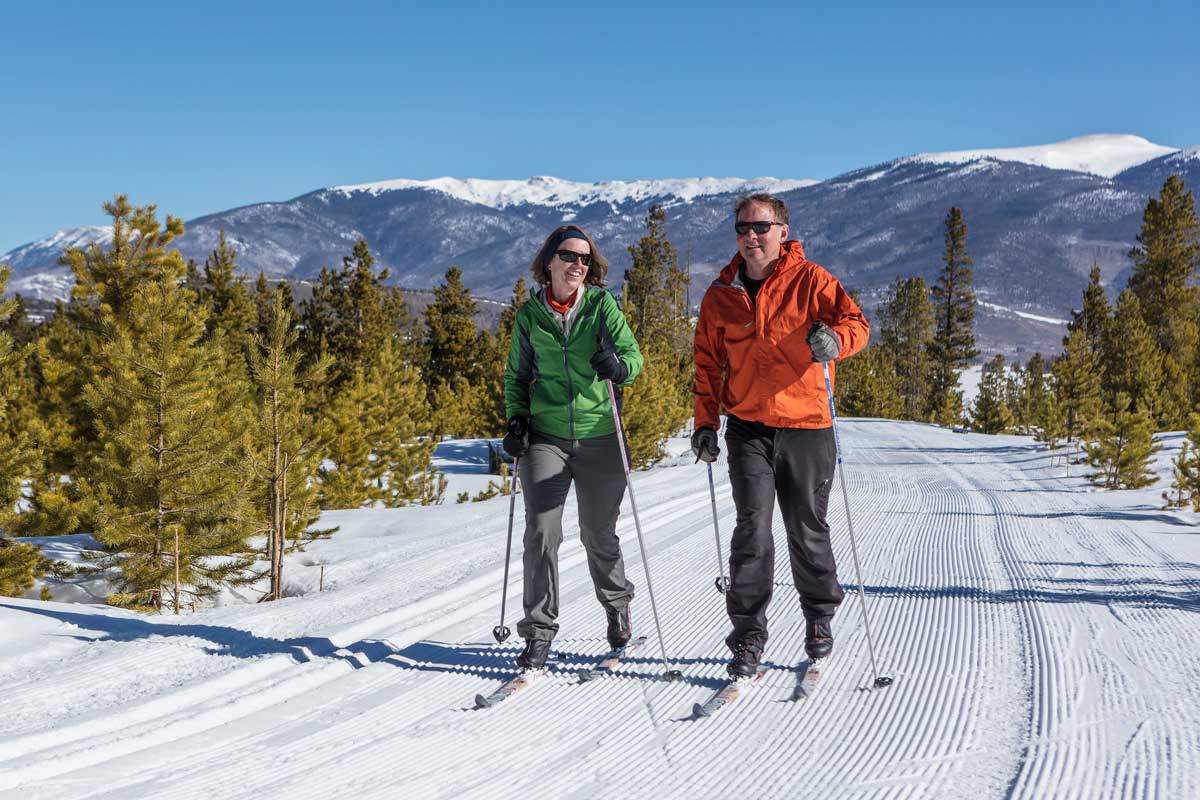 Man and woman smiling and laughing as they ski down the trails
